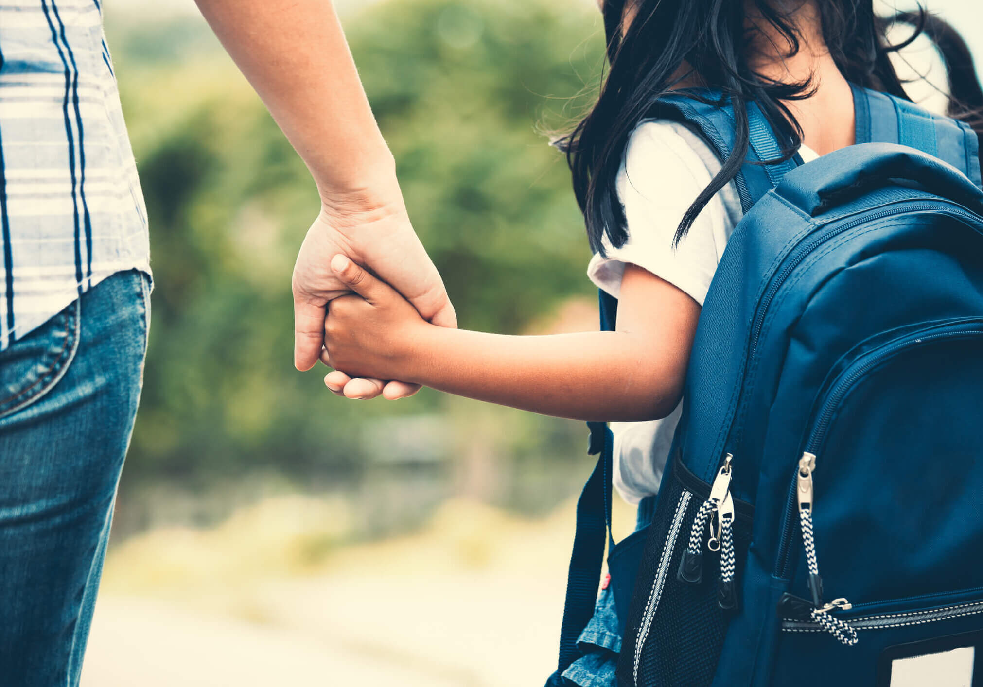 Back to school. Cute asian pupil girl with backpack holding her mother hand and going to school in vintage color tone