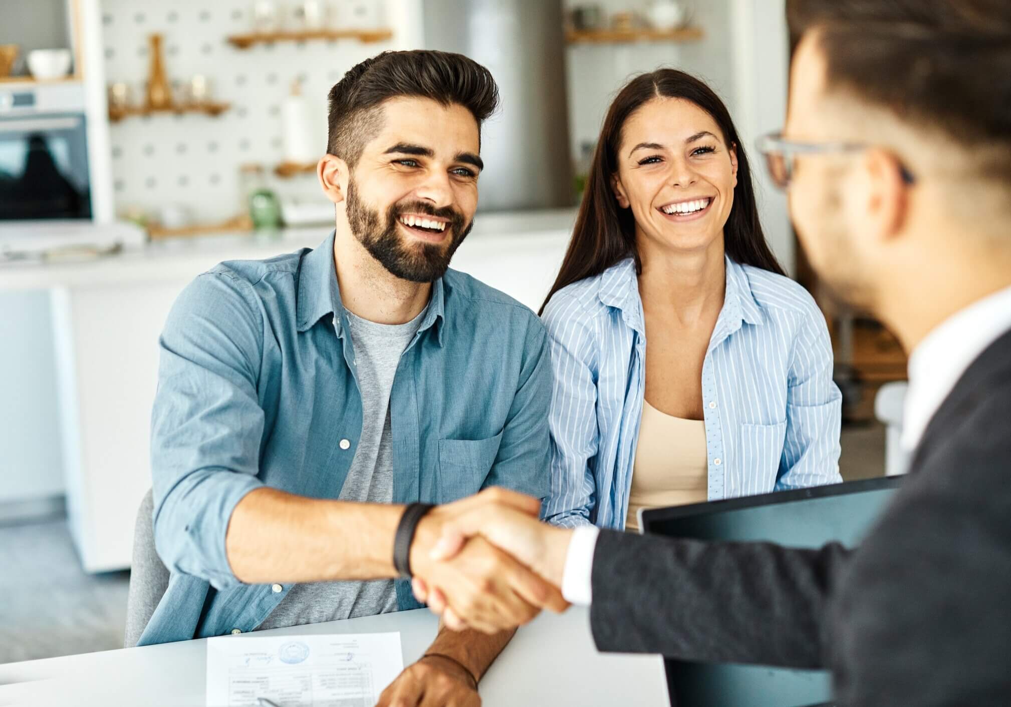 Real estate agent with couple shaking hands closing a deal and signing a contract