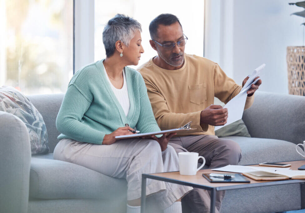 Finance, documents and senior couple on sofa with bills, paperwork and insurance checklist in home, life or asset management, Elderly black people on couch with financial, retirement or mortgage debt