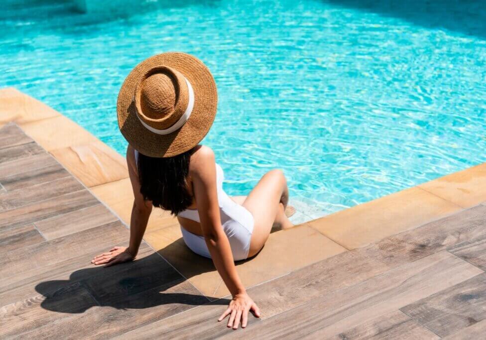 Beautiful girl in swimsuit relaxing by the pool during her summer holiday. Copy space. Summer and vacation, sunbathing wellness Lifestyle concept.