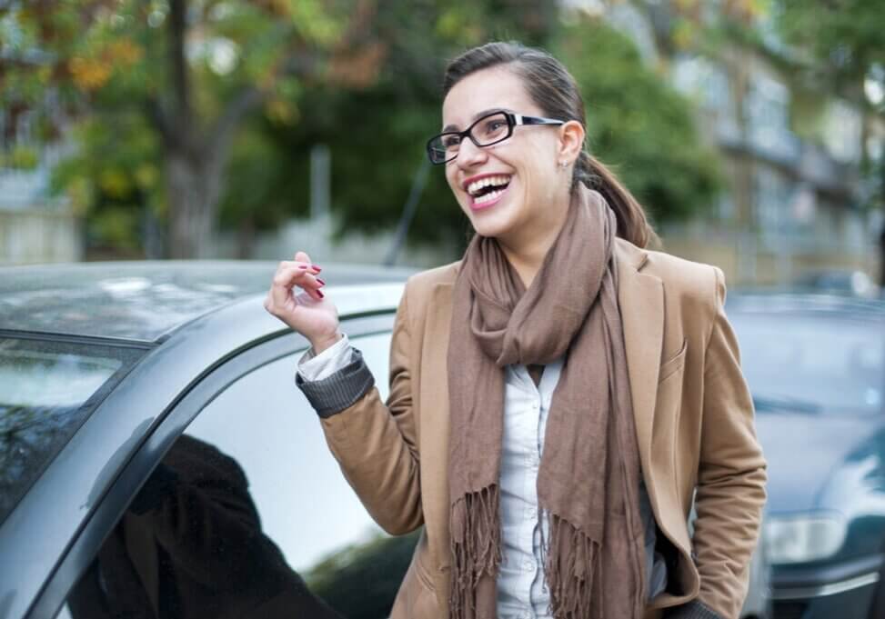 Woman laughing next to her car
