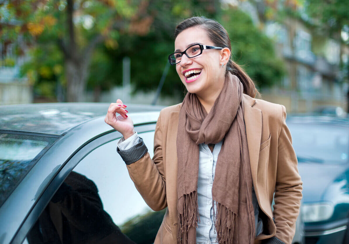 Woman laughing next to her car